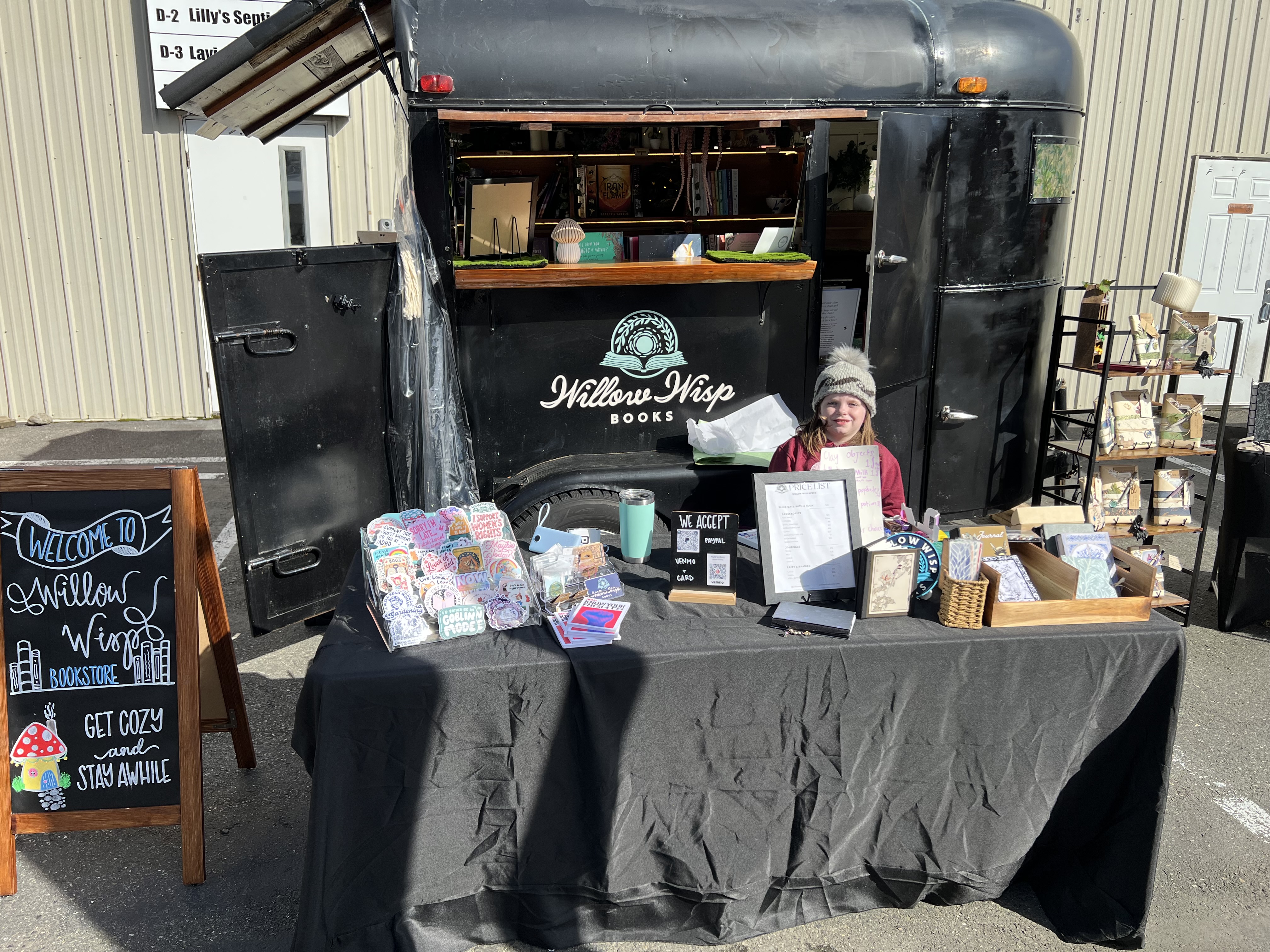 Kayla at the Willow Wisp Books trailer with goods on display